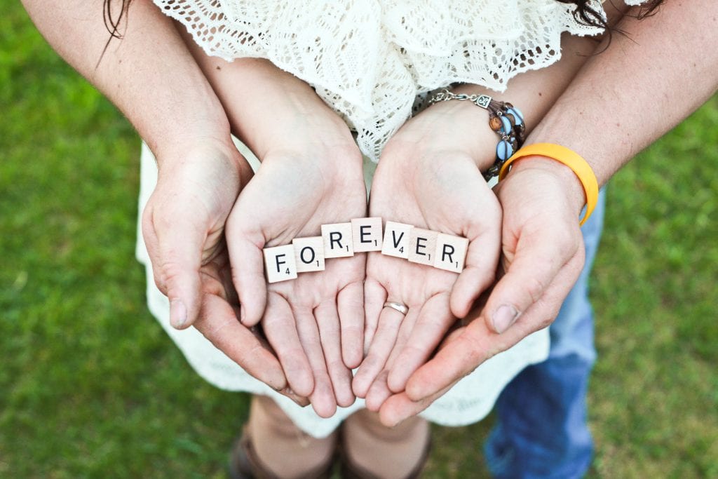 bride and groom hands holding lettters in forever